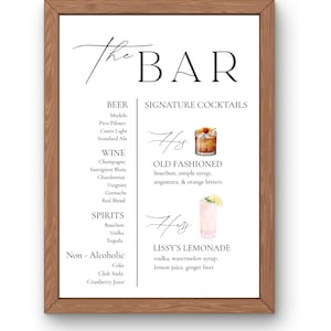 May include: A framed print with a wooden frame, featuring the text "The Bar" in elegant script. The print lists beer, wine, spirits, and non-alcoholic options, along with signature cocktail recipes for an Old Fashioned and Lissy's Lemonade.