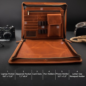 May include: Open, brown leather portfolio with multiple compartments. Features include a laptop pocket (9.8" x 12.6"), zippered pocket (7.1" x 9.4"), card slots, pen holders, a phone holder (3.5" x 5.5"), and a letter-size notepad holder. The portfolio is open, revealing its interior.