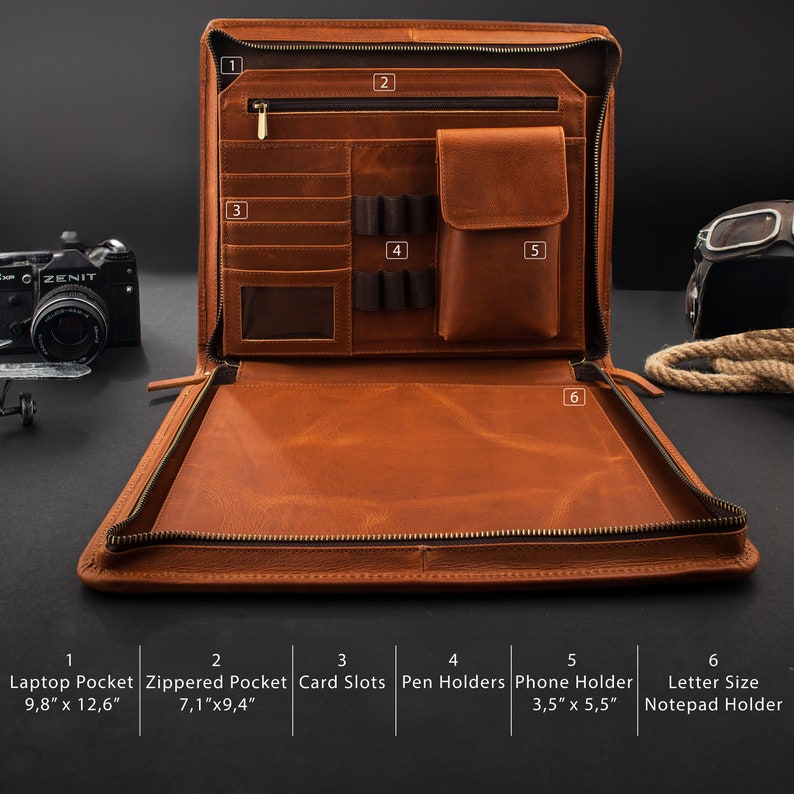May include: Open, brown leather portfolio with multiple compartments. Features include a laptop pocket (9.8" x 12.6"), zippered pocket (7.1" x 9.4"), card slots, pen holders, a phone holder (3.5" x 5.5"), and a letter-size notepad holder. The portfolio is open, revealing its interior.