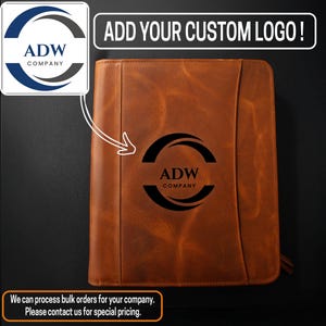 May include: A brown leather portfolio with a custom logo. The text "ADD YOUR CUSTOM LOGO!" is at the top. The logo is a black semi-circle with the text "ADW COMPANY" inside. The portfolio has a zipper closure.