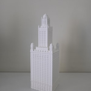 May include: A white architectural model of a tall building with intricate details. The model features a rectangular base with a tower that has a domed top. The building has many windows and decorative elements.