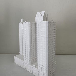 Peut inclure: Maquette architecturale blanche d'un immeuble à plusieurs étages avec des fenêtres et des façades détaillées. Le modèle comprend une section de tour et une petite structure de toit. Le bâtiment est de couleur claire et semble être fait d'un matériau solide.
