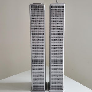 Könnte beinhalten: Ein Modell der Twin Towers, zwei hohe, graue Gebäude mit einer weißen Antenne auf dem rechten Gebäude.