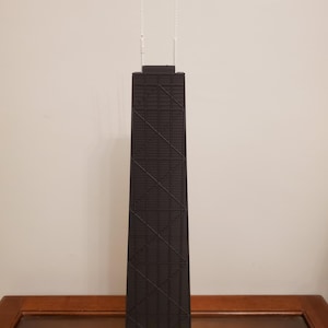 May include: A black and white model of a skyscraper with a grid pattern. The model is made of plastic and has a detailed design.