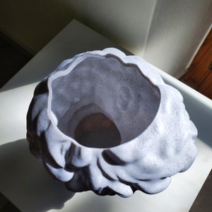 May include: A white ceramic planter with a textured, organic shape resembling a cloud or a brain. The planter has a wide opening and a smooth, rounded interior.