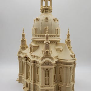 Può includere: Un modello dettagliato di una chiesa stampato in 3D con una cupola, dettagli intricati e un colore beige.