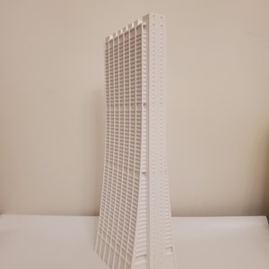 Könnte beinhalten: Ein weißes Architekturmodell eines Wolkenkratzers. Das Gebäude hat viele Fenster und ein einzigartiges, geschwungenes Design. Das Modell besteht aus einem soliden weißen Material und steht vor einem neutralen Hintergrund.
