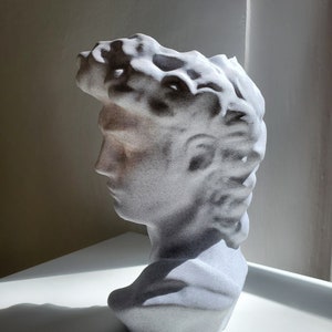 May include: White plaster bust sculpture of a man with a textured surface. The bust is a modern interpretation of a classic sculpture.