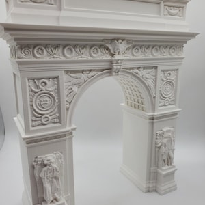 May include: A white, detailed model of the iconic New York City archway, the Washington Square Arch. The model is made of a smooth, white material and features intricate carvings and details.