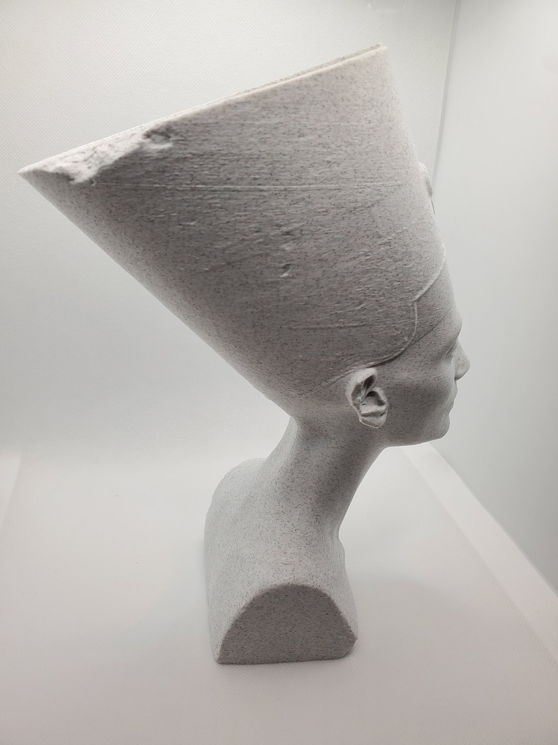K&ouml;nnte beinhalten: Wei&szlig;e B&uuml;ste einer &auml;gyptischen K&ouml;nigin mit traditioneller Kopfbedeckung. Die Skulptur ist aus einem strukturierten Material gefertigt, das an Stein erinnert.