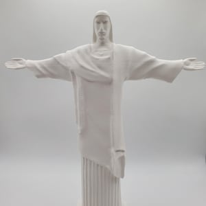 May include: White plaster statue of Jesus Christ with outstretched arms. The statue is standing on a square base.