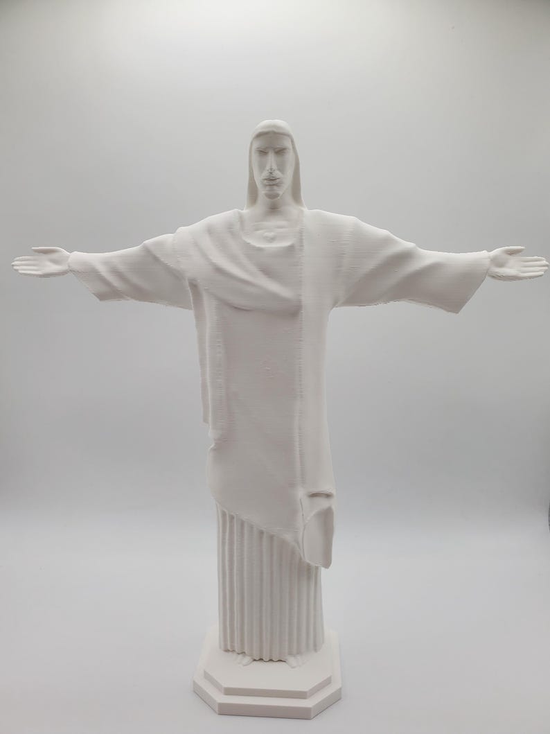 May include: White plaster statue of Jesus Christ with outstretched arms. The statue is standing on a square base.
