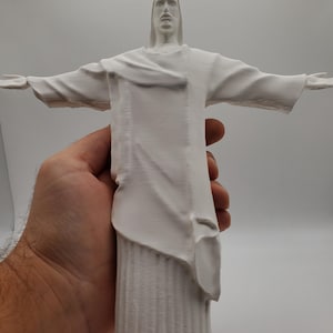 May include: White plastic figurine of the Christ the Redeemer statue in Rio de Janeiro, Brazil.