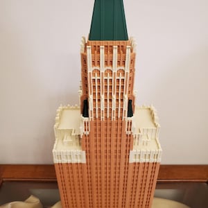 Könnte beinhalten: Ein detailliertes Modell eines hohen Backsteingebäudes mit einem grünen Dach. Das Gebäude hat viele Fenster und dekorative Details.
