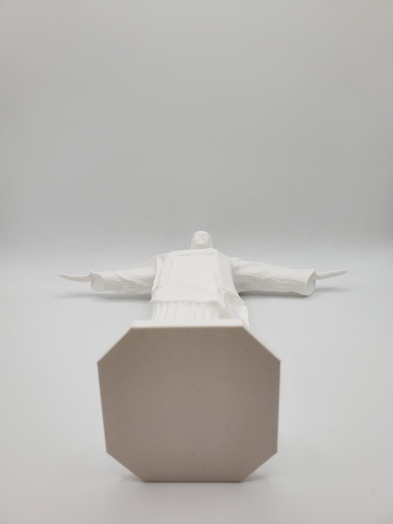 May include: White ceramic statue of Christ the Redeemer with outstretched arms, standing on an octagonal base.
