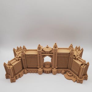 Könnte beinhalten: Ein detailliertes 3D-gedrucktes Modell eines großen, verzierten Hotelgebäudes. Das Modell besteht aus hellbraunem Kunststoff und weist komplizierte Details auf, darunter Fenster, Balkone und einen großen Torbogen.
