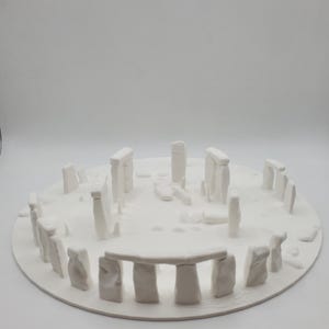 Könnte beinhalten: Ein weißes 3D-gedrucktes Modell von Stonehenge, einem prähistorischen Monument in England. Das Modell besteht aus glattem, weißem Kunststoff und hat einen Durchmesser von etwa 25 cm.
