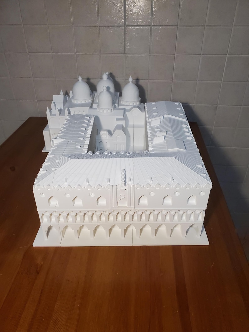 May include: A white 3D printed model of a building with multiple domes and a courtyard. The model is detailed with arches and windows.