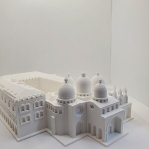 May include: A white 3D printed model of a building with multiple domes and arches. The model is detailed and intricate, with visible windows and other architectural features.