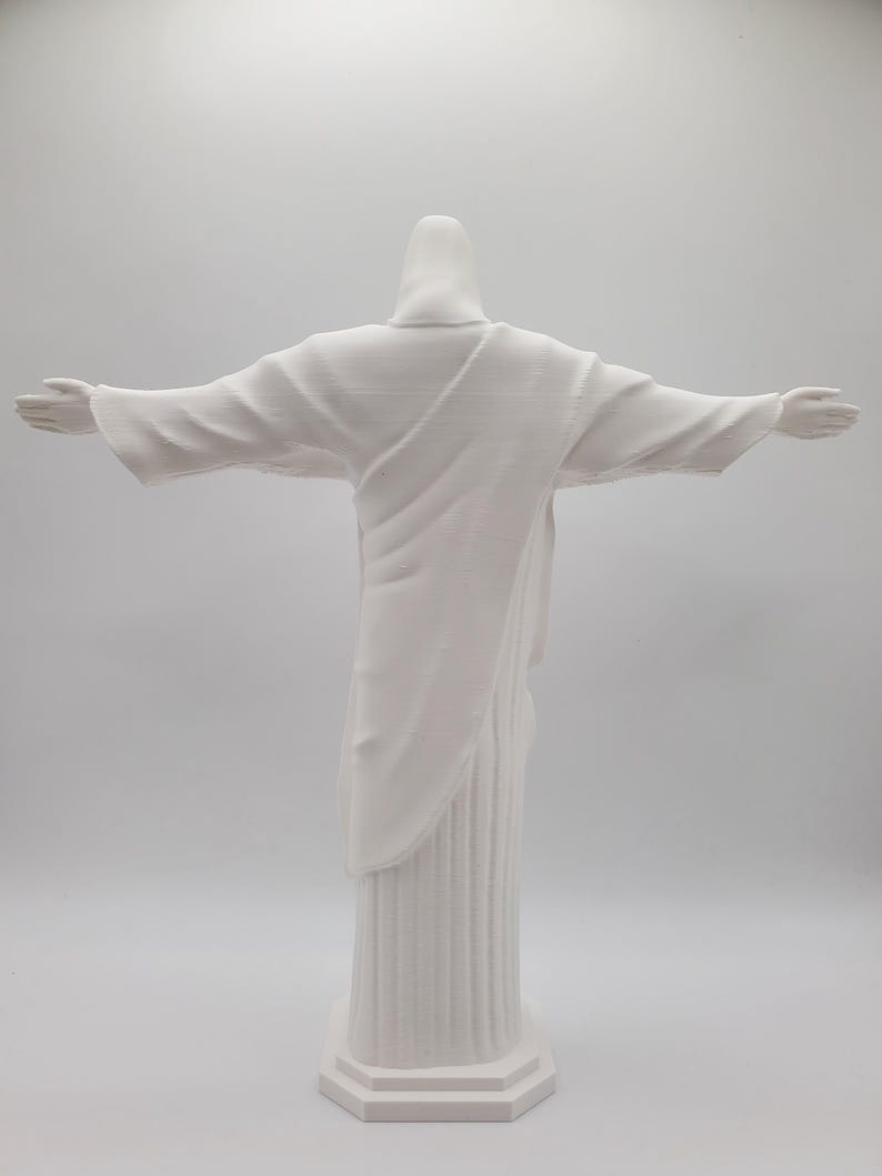 May include: White painted statue of Jesus Christ with outstretched arms, standing on a pedestal.