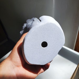 May include: A white ceramic bust sculpture with a textured surface. The bust has a hole in the bottom for drainage.