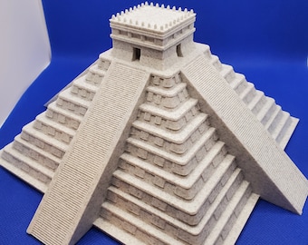 May include: A beige 3D printed model of a Mayan pyramid with a square base and a stepped structure. The pyramid has a small rectangular structure on top with a flat roof.