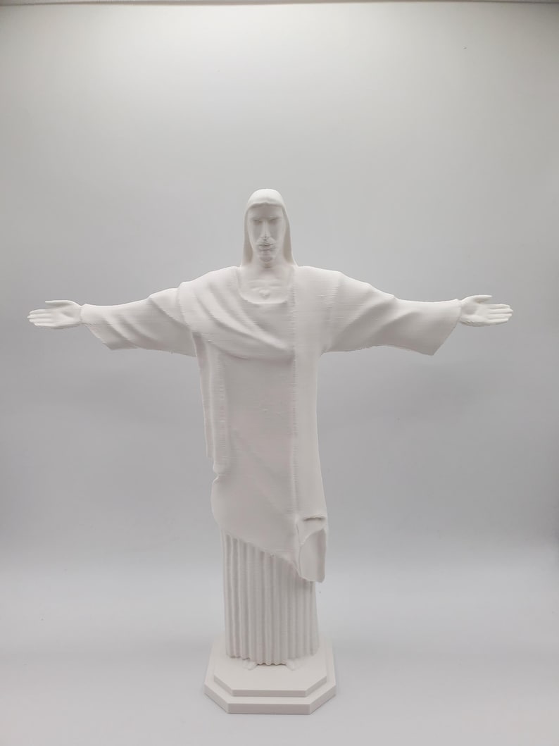 May include: White plastic figurine of the Christ the Redeemer statue with outstretched arms.