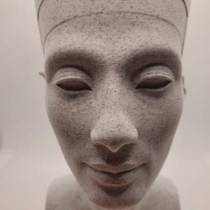 K&ouml;nnte beinhalten: Eine wei&szlig;e B&uuml;ste einer Frau mit Kopfbedeckung. Die Skulptur hat ein detailliertes Gesicht mit geschlossenen Augen und einem dezenten L&auml;cheln.
