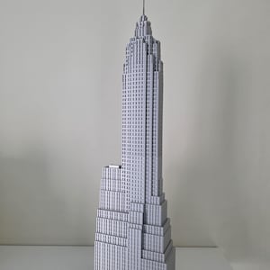 Peut inclure: Une maquette grise détaillée de l'Empire State Building. Le modèle présente le design en gradins et l'antenne emblématiques, mettant en valeur les détails architecturaux du célèbre gratte-ciel. Le bâtiment est posé sur un fond uni.