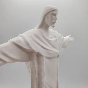 May include: White plaster statue of Jesus Christ with outstretched arms. The statue is a depiction of the iconic Christ the Redeemer statue in Rio de Janeiro, Brazil.