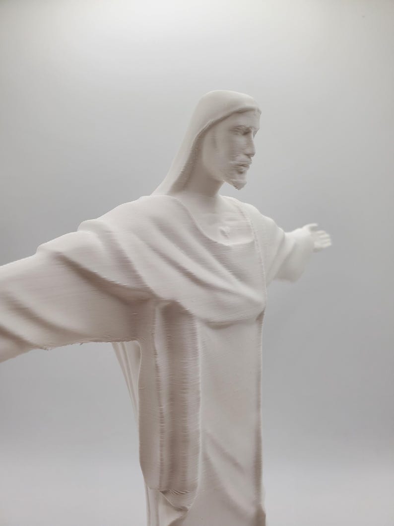 May include: White plaster statue of Jesus Christ with outstretched arms. The statue is a depiction of the iconic Christ the Redeemer statue in Rio de Janeiro, Brazil.