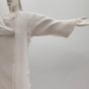 May include: A white plaster sculpture of a person with arms outstretched, resembling the famous Christ the Redeemer statue in Rio de Janeiro.