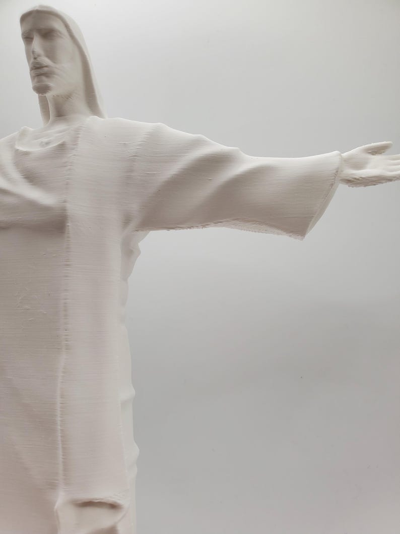 May include: A white plaster sculpture of a person with arms outstretched, resembling the famous Christ the Redeemer statue in Rio de Janeiro.