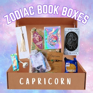 May include: A brown box labelled "ZODIAC BOOK BOXES" and "CAPRICORN" contains a bookmark, keychain, stickers, a tarot card, a bracelet, a snack, and a small bag. The box is set against a colourful background. The items are themed around Capricorn.