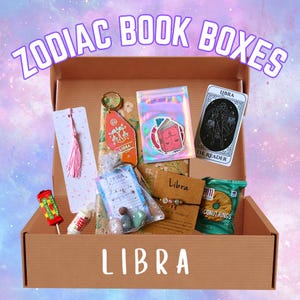 Puede incluir: Una caja de regalo con temática de Libra llena de varios artículos. La caja contiene un marcapáginas con borla rosa, un llavero, una carta del tarot, una pulsera, una bolsa de piedras, una piruleta y una bolsa de aros de coco. La caja está etiquetada como "ZODIAC BOOK BOXES" y "LIBRA".