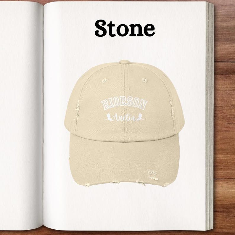 Op de afbeelding: Een baseballpet van steenkleur met een distressed look, met de tekst "RIORSON Avetia" in wit geborduurd.