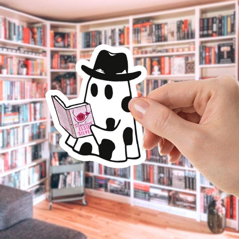 May include: A black and white sticker featuring a cartoon ghost wearing a fedora and reading a book. The book cover reads "Flawless Elsie Silve" with a rose illustration. The ghost has black spots and is set against a blurred bookshelf background.