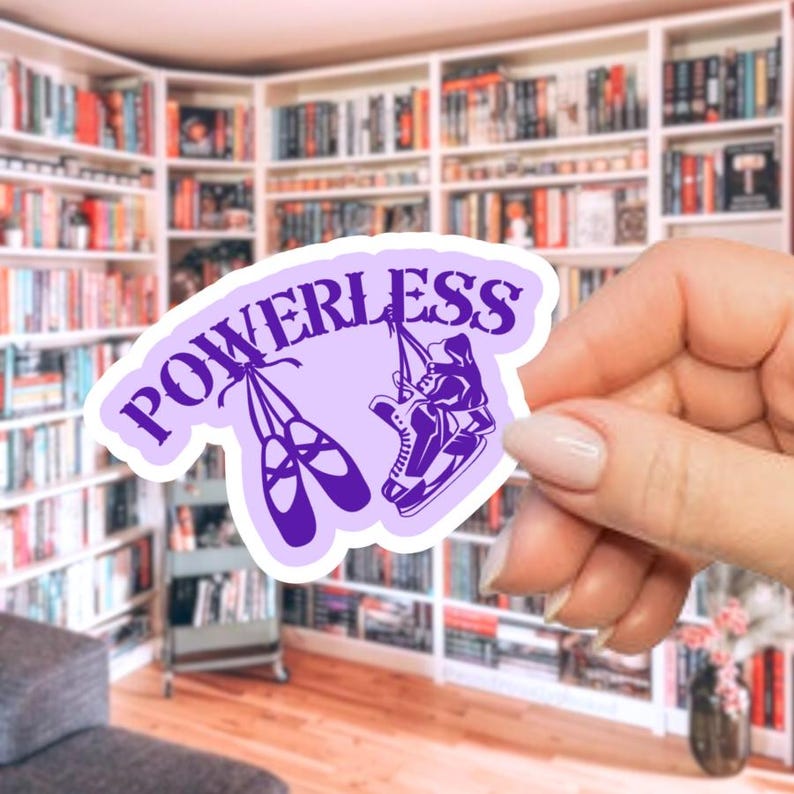 May include: A light purple sticker with the word "POWERLESS" in a stylized font. The sticker features illustrations of ballet shoes and ice skates. The background shows a room with bookshelves filled with books.