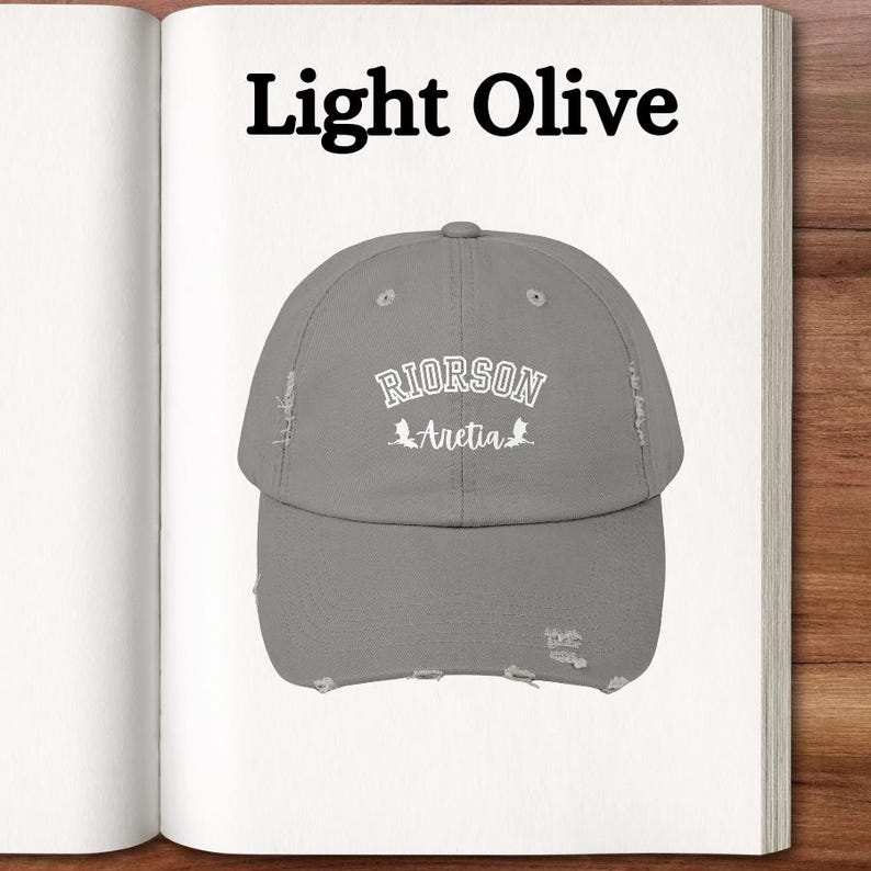 Op de afbeelding: Een licht olijfgroene, verweerde baseballpet met de tekst "RIORSON Aretia" in wit geborduurd.
