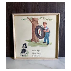 May include: Framed vintage print featuring a boy swinging on a tire swing tied to a tree. A black and white dog looks on. The text "Here, Spot. Here, Spot. Look here." is printed below the image. The frame is light wood.