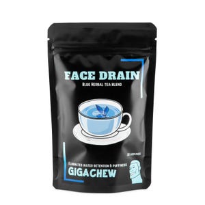Pode incluir: Uma bolsa preta com uma etiqueta branca que diz "FACE DRAIN BLUE HERBAL TEA BLEND". A etiqueta também apresenta uma ilustração de desenho animado de uma xícara de chá azul com uma flor flutuando nela. A bolsa tem uma etiqueta branca na parte inferior que diz "ELIMINATES WATER RETENTION & PUFFINESS GIGACHEW" e uma ilustração de desenho animado do rosto de uma pessoa. A bolsa tem uma etiqueta branca na parte superior que diz "20 SERVINGS".