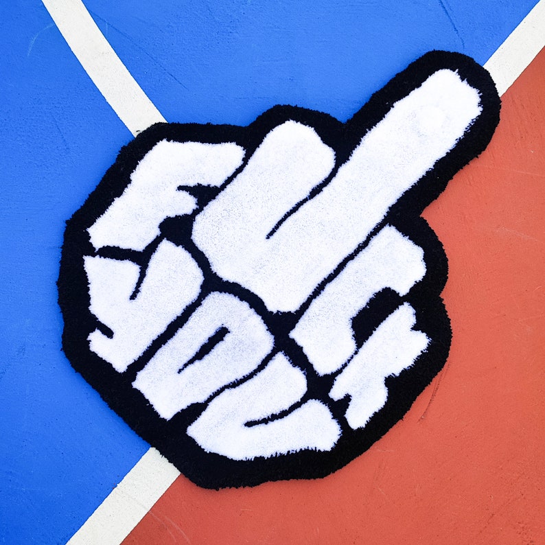 May include: A white rug shaped like a hand giving the middle finger. The rug is outlined in black and is on a blue and red background.