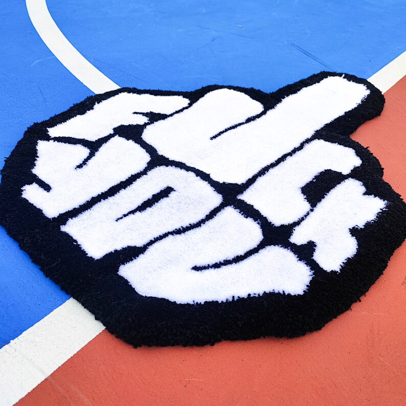 May include: A black and white rug shaped like a hand with the word "WE" written in white on a black background.