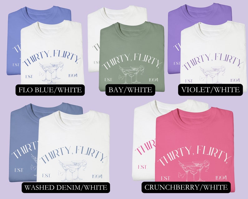 May include: Six folded t-shirts in different colors with the text "THIRTY, FLIRTY EST 1994" and a martini glass graphic. The colors are: Flo Blue/White, Bay/White, Violet/White, Washed Denim/White, and Crunchberry/White.