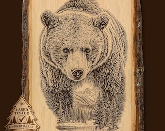 May include: A detailed wood carving of a grizzly bear, facing forward, with a mountain and forest scene in the background. The artwork is on a natural wood slab with bark edges. The image includes a "Laser Tested" seal for commercial use.