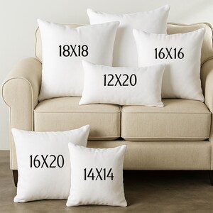 a beige couch with six white throw pillows of different sizes, arranged in a row.