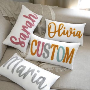 three decorative pillows on a couch with a name on them
