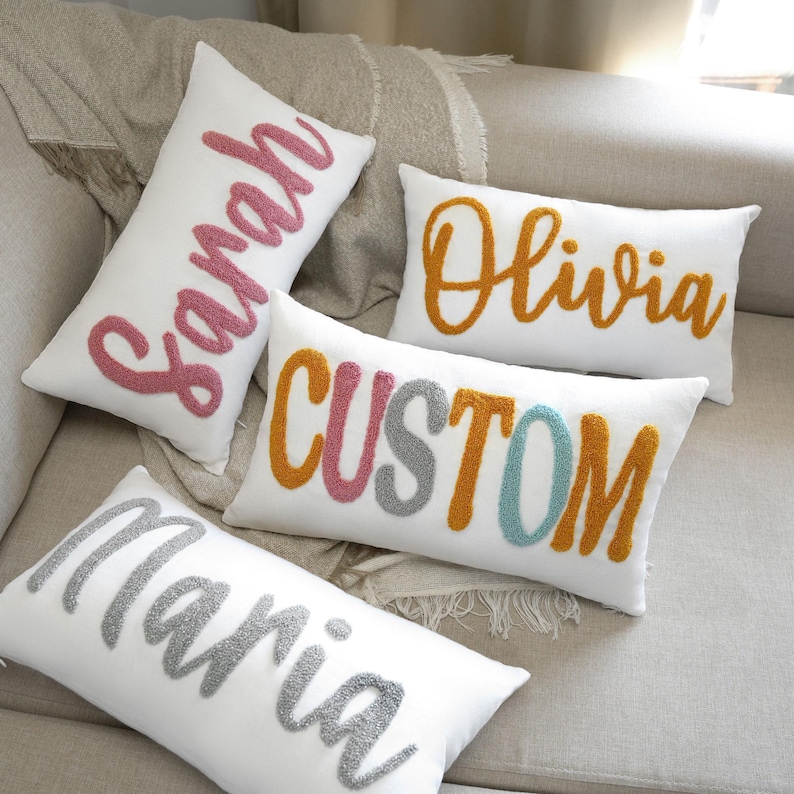three decorative pillows on a couch with a name on them