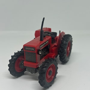 May include: Red toy tractor with black wheels and a black exhaust pipe. The tractor has the text "VOLVO BM" on the front.