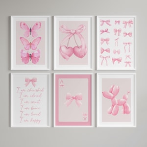 May include: Six framed art prints with pink watercolor designs. The prints feature butterflies, cherries, bows, and a balloon dog. One print has the text "I am cherished, adored, smart, brave, loved, happy".